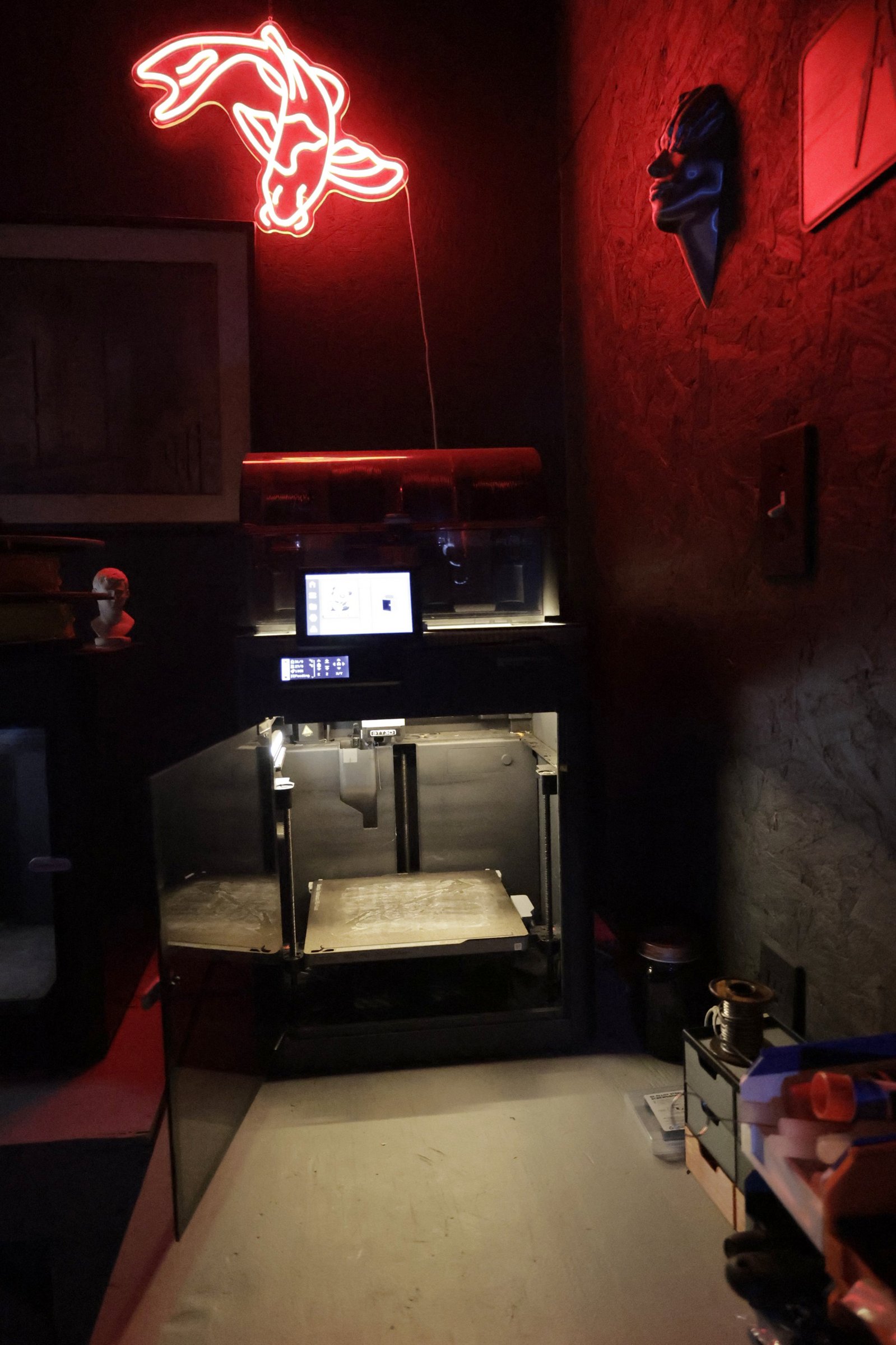 One of TacticalTech3D's enclosed 3D printers on the shop bench, door open under the workshop's red neon sign. Photograph by Digital Life Concepts.