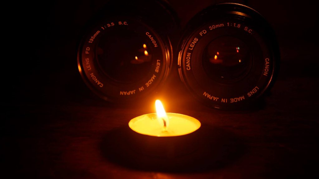 Candle and camera lenses, symbolizing SB Visuals photography craft